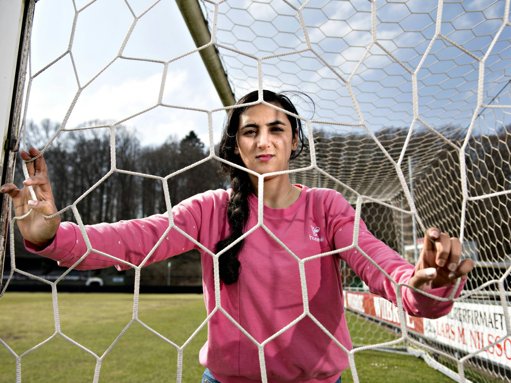 Khalida Popa posiert in einem Tor, sie schaut durch das Tornetz.