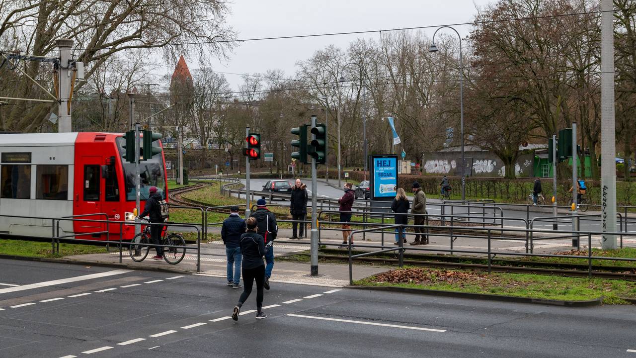 Fußgänger passieren einen Bahnübergang an der Aachener Straße