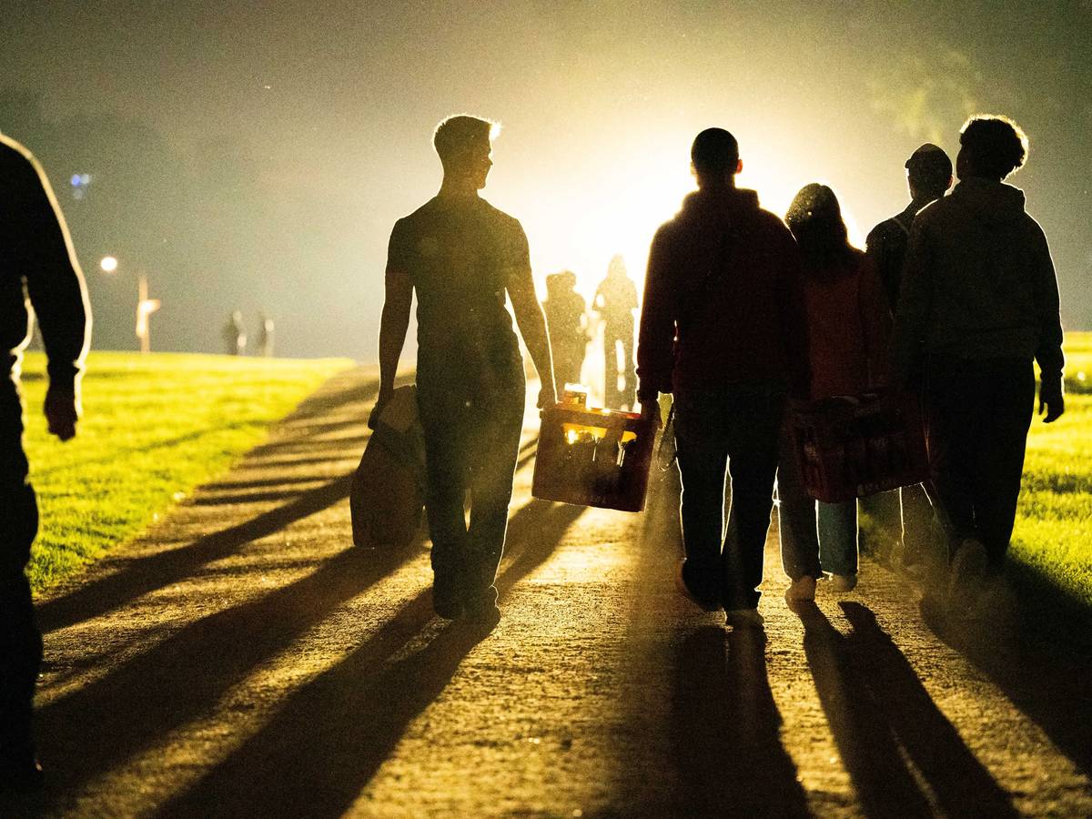 Eine Gruppe von jungen Leuten geht mit einem Getränkekasten zum Aachener Weiher.