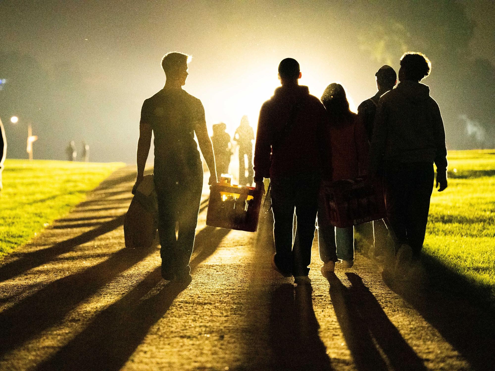 Eine Gruppe von jungen Leuten geht mit einem Getränkekasten zum Aachener Weiher.