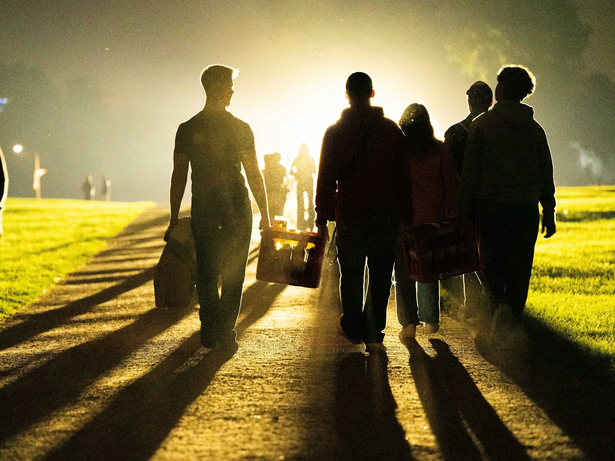 Eine Gruppe von jungen Leuten geht mit einem Getränkekasten zum Aachener Weiher.
