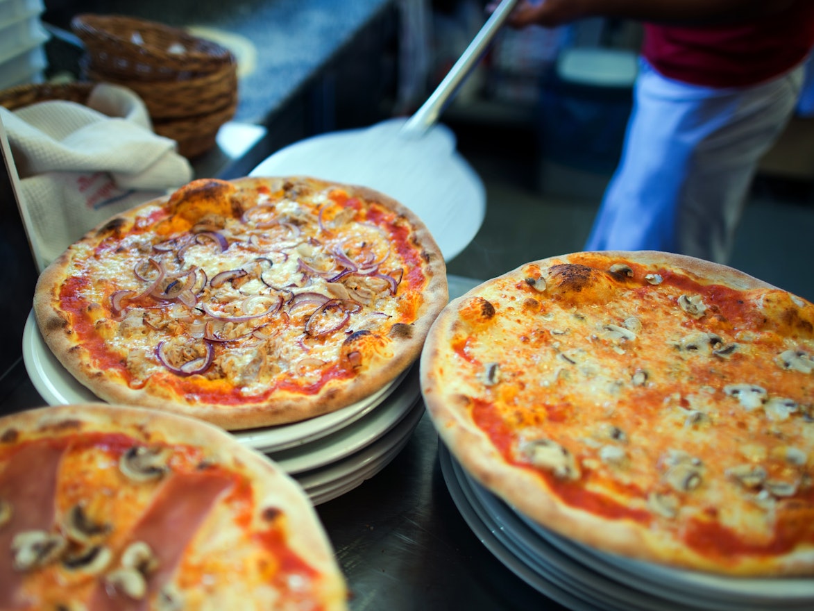 Wer Hunger auf Pizza hat, sollte in NRW bestellen. Das Online-Portal Speisekartenweb.de hat die Preise analysiert. Unser Foto zeigt, wie eine Pizza auf einen Teller geschoben wird.