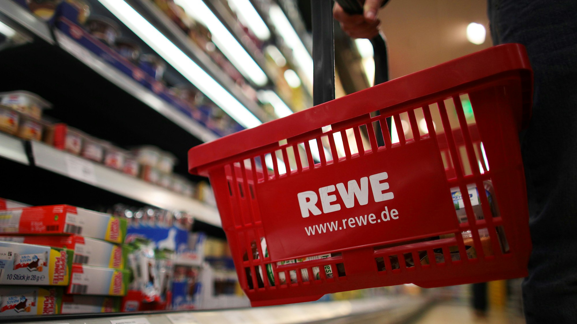 Bei Rewe wird Apfelmark der Firma ODW Lebensmittel GmbH zurückgerufen. Unser Symbolfoto zeigt einen Kunden mit Einkaufskorb vor einem Regal bei Rewe.