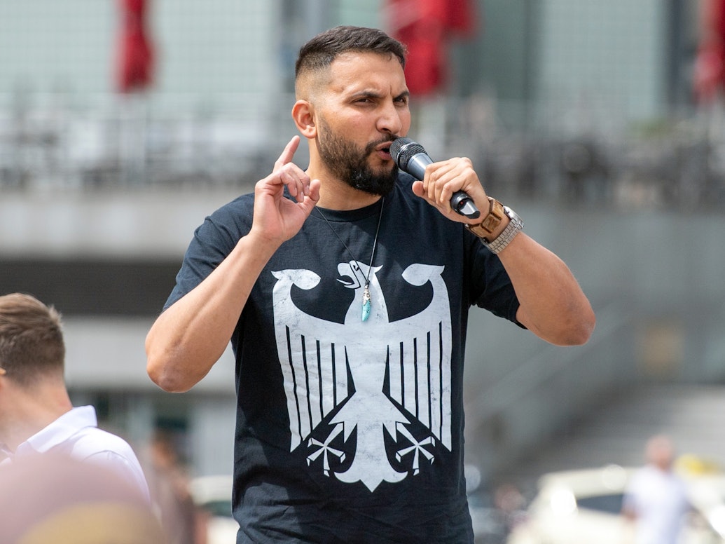 Der Verschwörungsprediger Attila Hildmann spricht im Juli 2020 bei einer Anti-Corona-Demo in Berlin. Er trägt ein schwarzes Shirt mit dem Bundesadler.