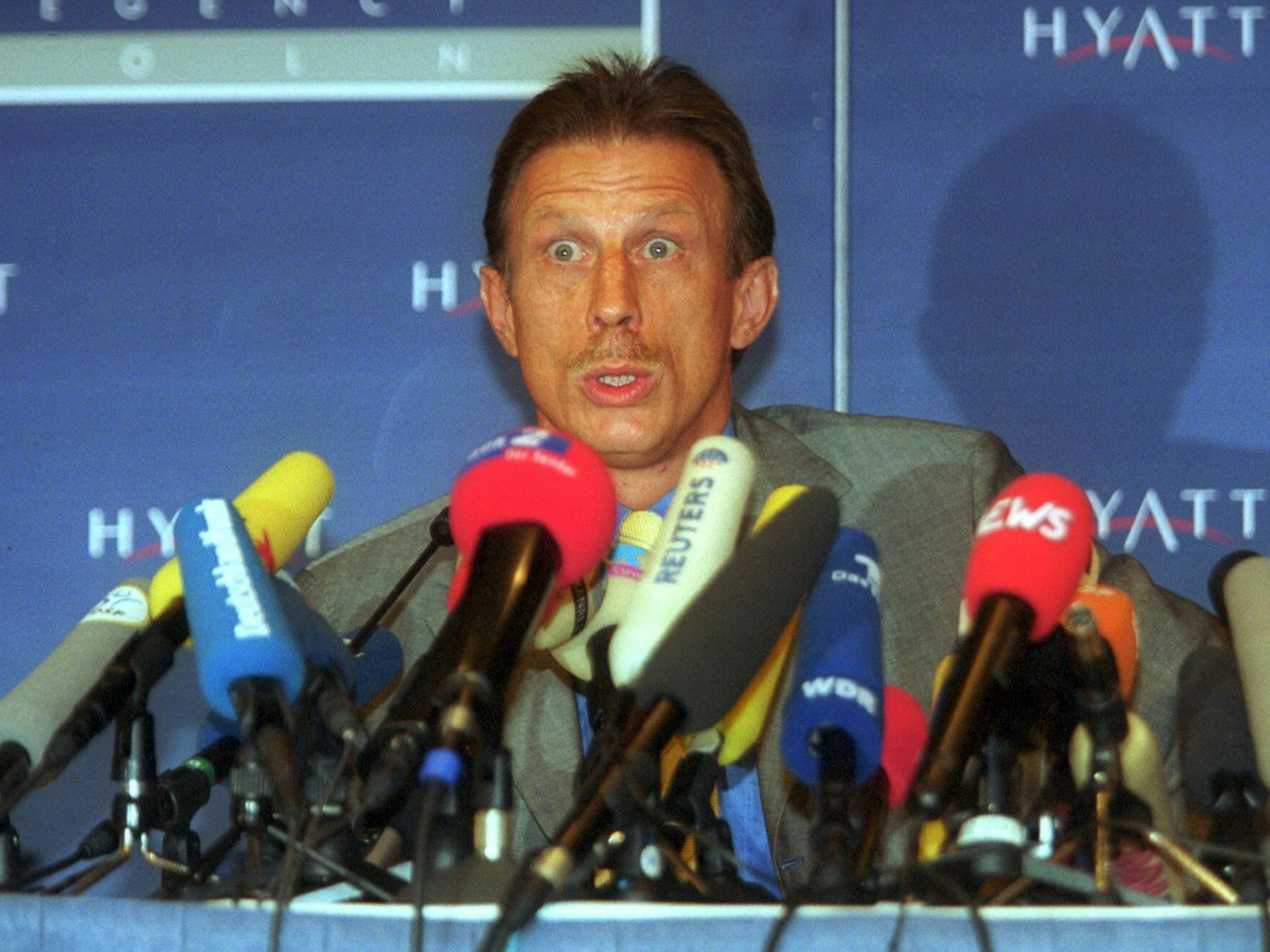 Daum sitzt vor mehreren Mikrofonen, hat die Augen weit aufgerissen.