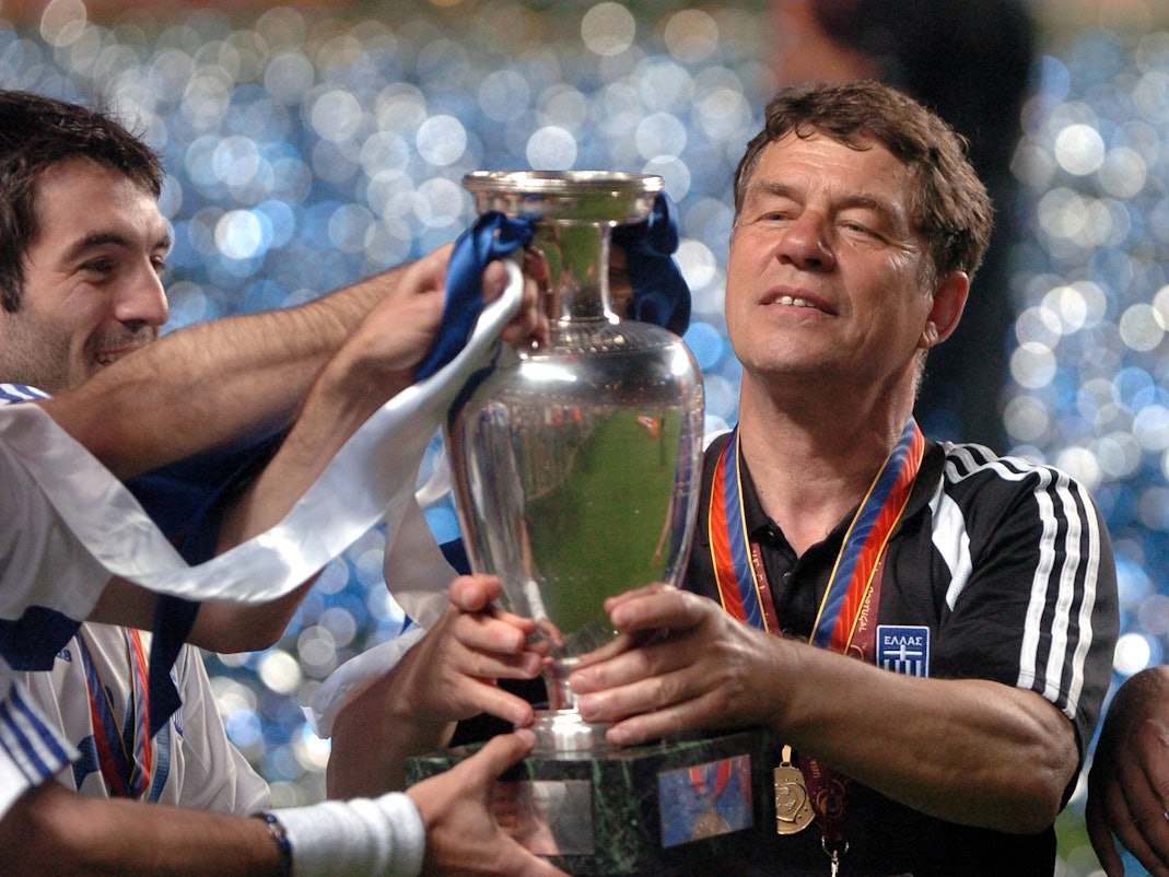 Otto Rehhagel hält die EM-Trophäe in den Händen und betrachtet sie.