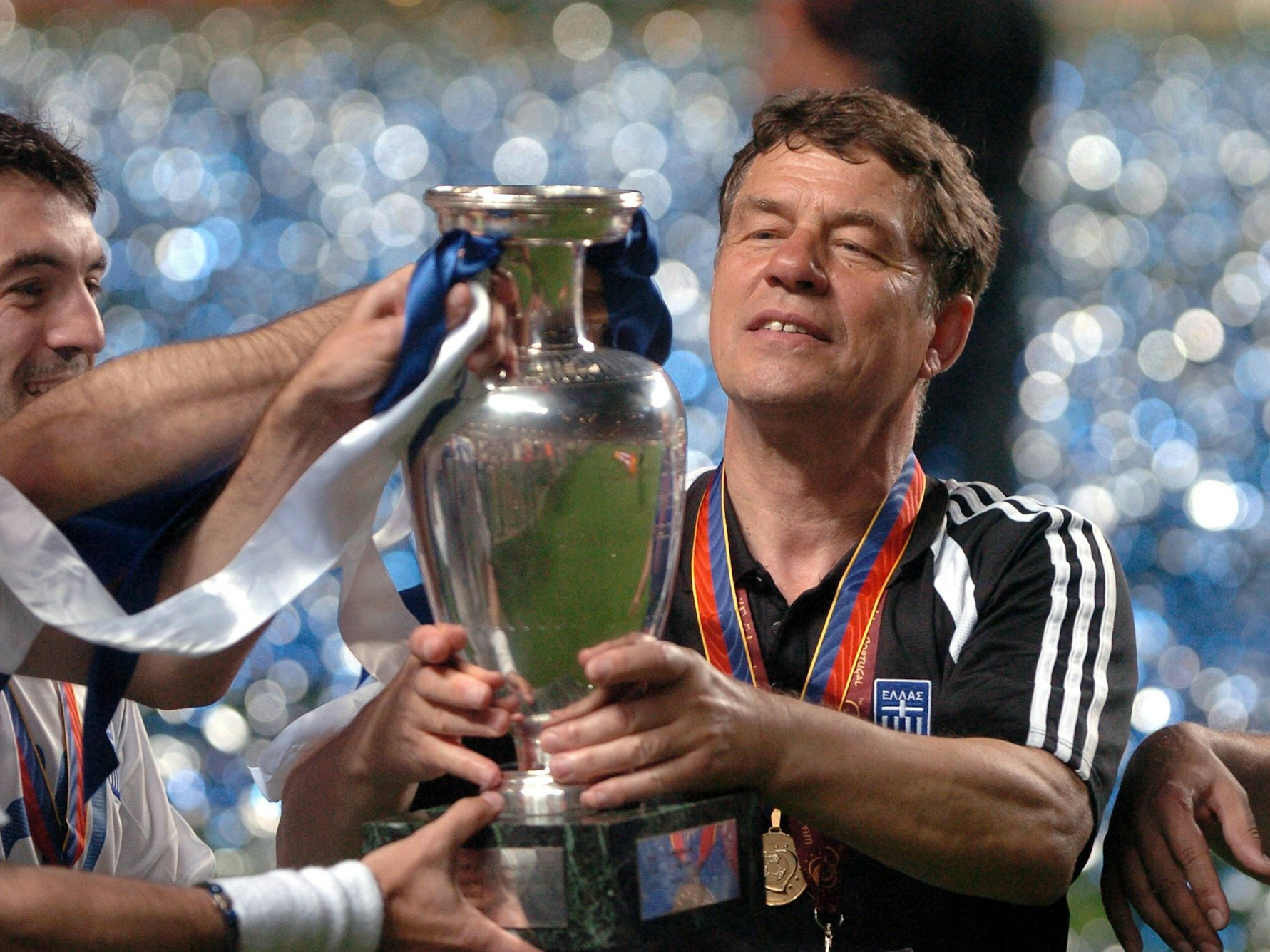 Otto Rehhagel hält die EM-Trophäe in den Händen und betrachtet sie.