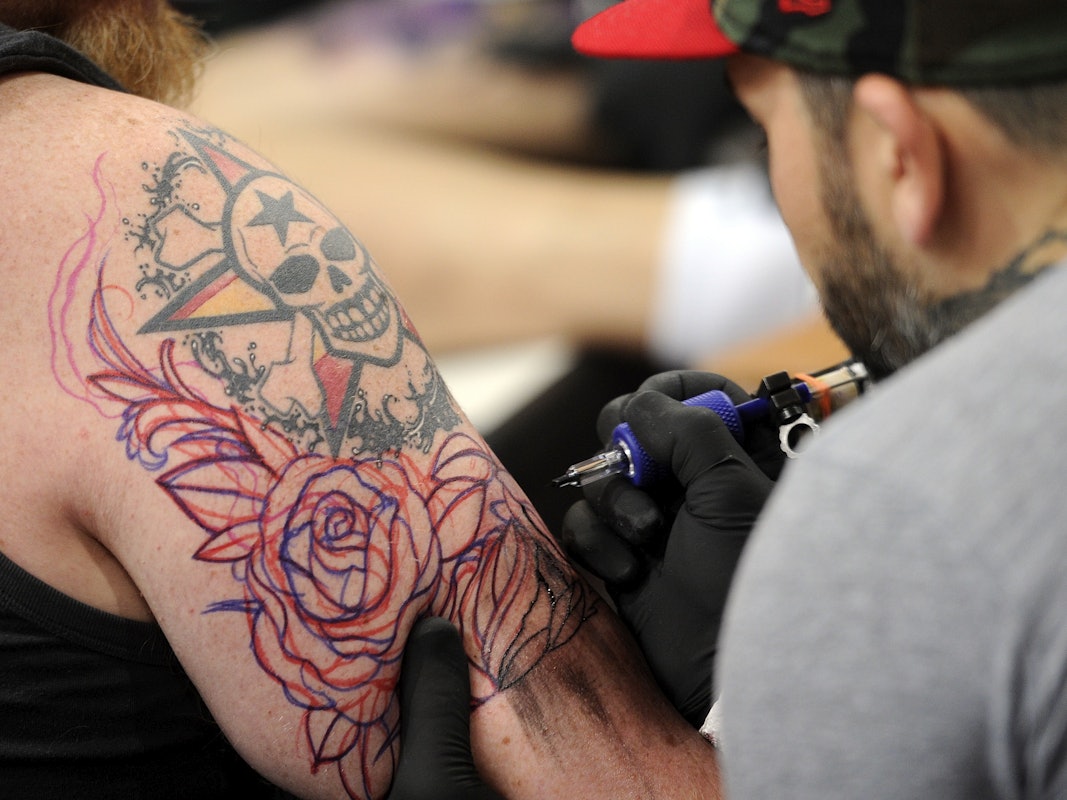 Ein Tätowierer sticht ein Tattoo.