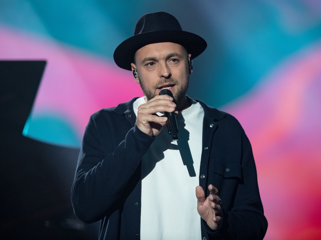 Max Mutzke singt auf einer Benefizgala im schwarzen Anzug.
