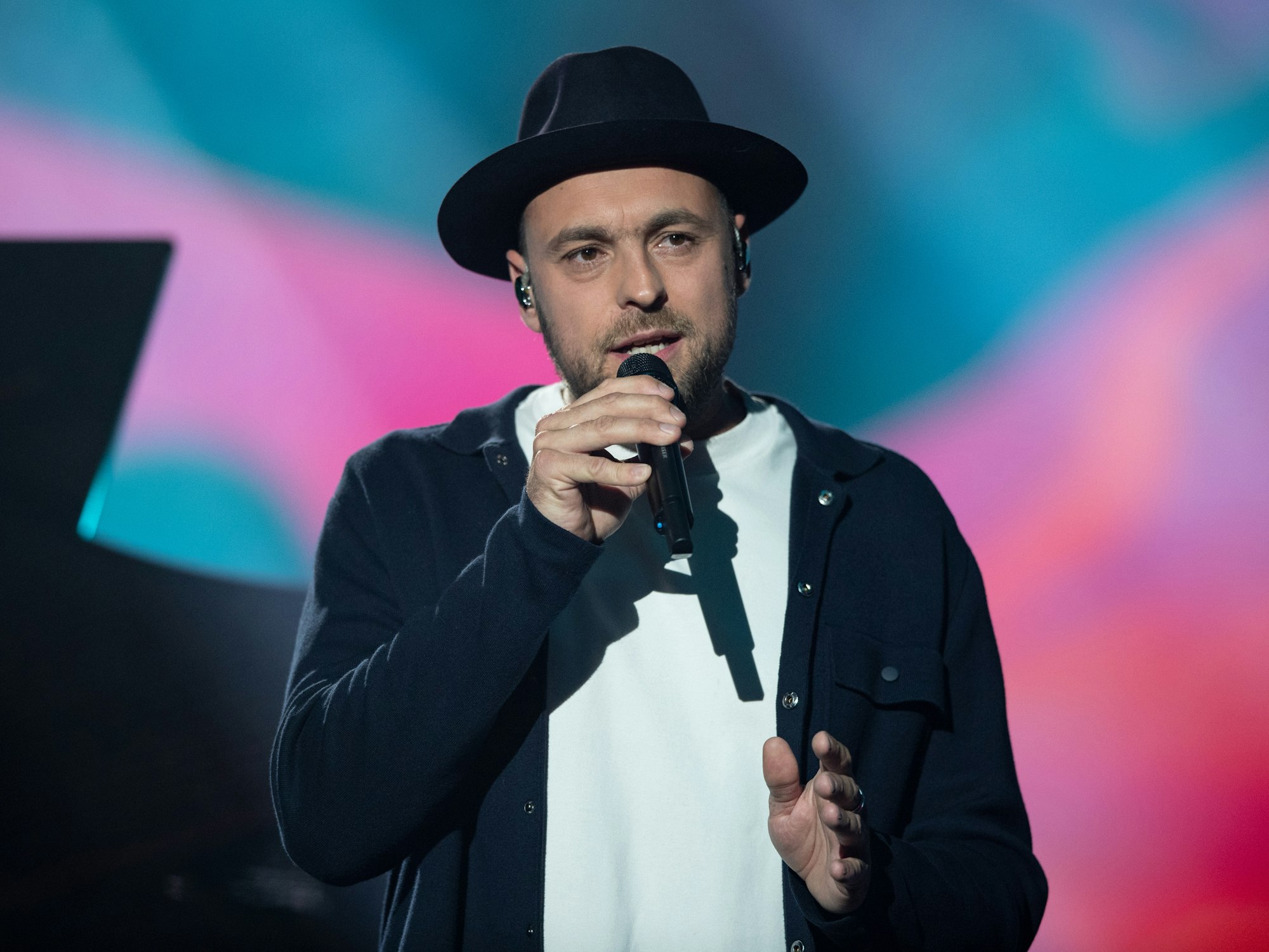 Max Mutzke singt auf einer Benefizgala im schwarzen Anzug.