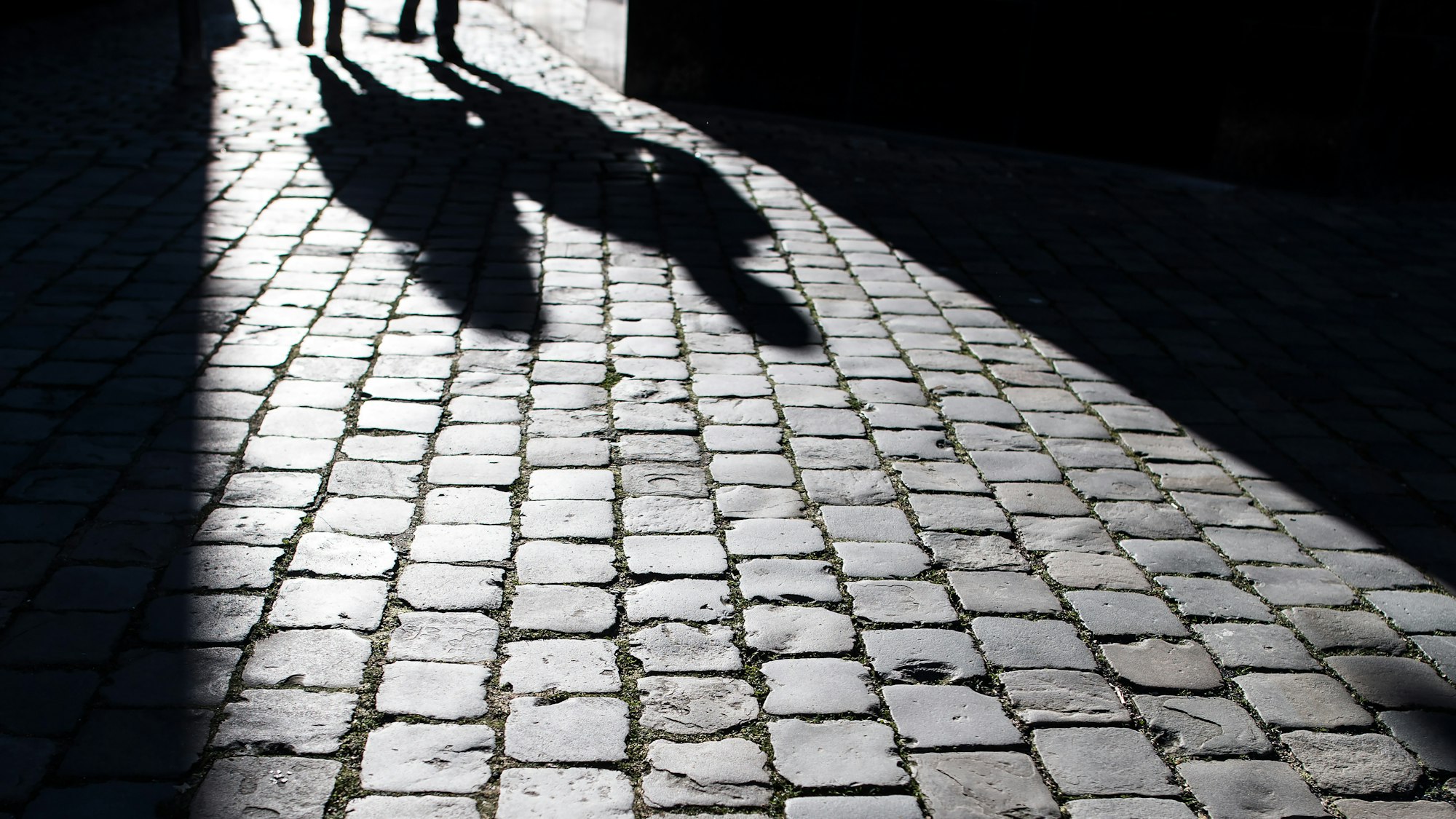 Fußgänger werfen am 21. Januar 2019 in der Aachener Innenstadt ihre Schatten auf das Pflaster.