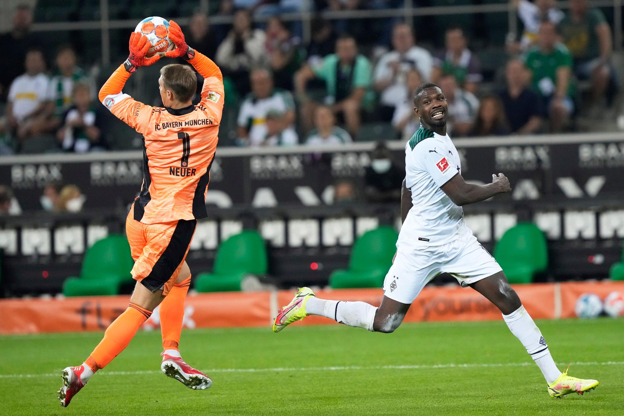 Manuel Neuer hat den Ball vor Marcus Thuram