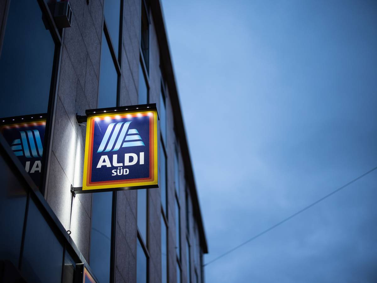 Das Logo einer Aldi Süd Filiale, fotografiert in einer Fußgängerzone der Düsseldorfer Innenstadt, ist beleuchtet am Abend zu sehen.