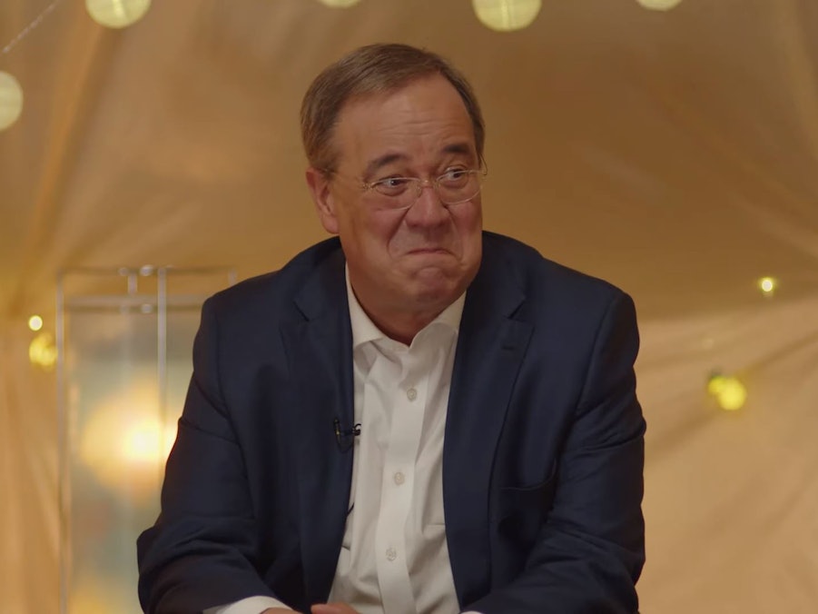 Armin Laschet sitzt im Zelt mit den beiden Kinderreportern Pauline und Romeo und verzieht erstaunt sein Gesicht.