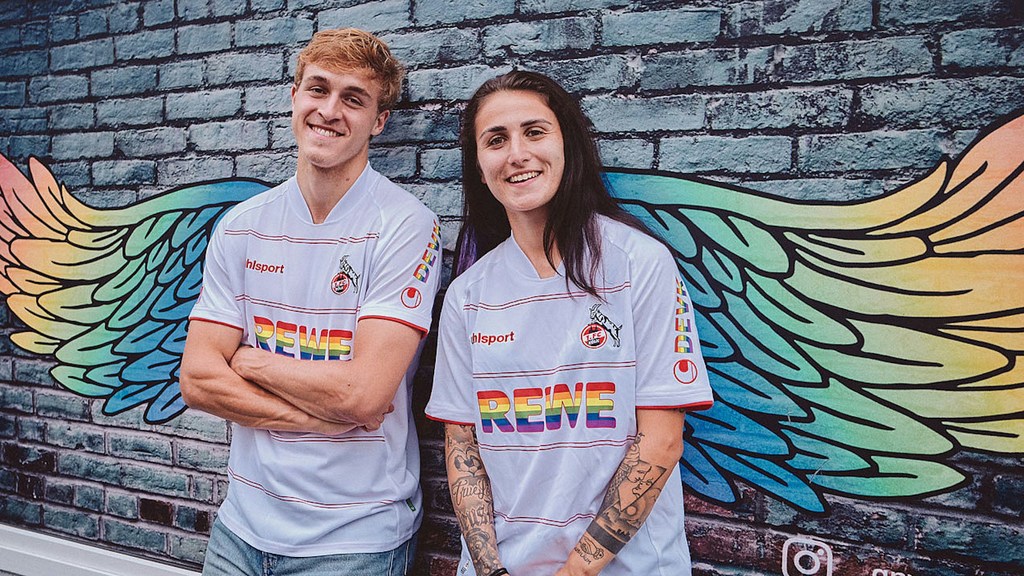 Timo Hübers und Francesca Calo posieren im Sondertrikot des 1. FC Köln.