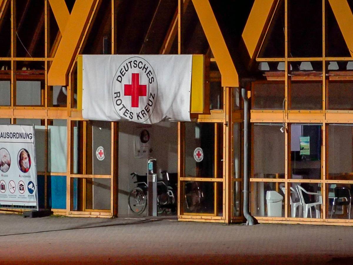 Eine Rot-Kreuz-Fahne hängt über dem Eingang zum Impfzentrum in Eich. Im sächsischen Vogtlandkreis hat es einen Brandanschlag auf ein Impfzentrum gegeben.