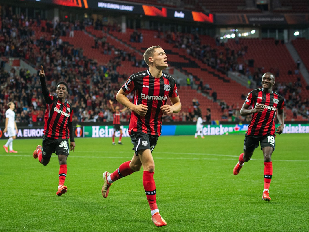 Leverkusens Torschütze Florian Wirtz (M) jubelt nach seinem Treffer zur 2:1 Führung. Daneben laufen Jeremie Frimpong (l) und Moussa Diaby.