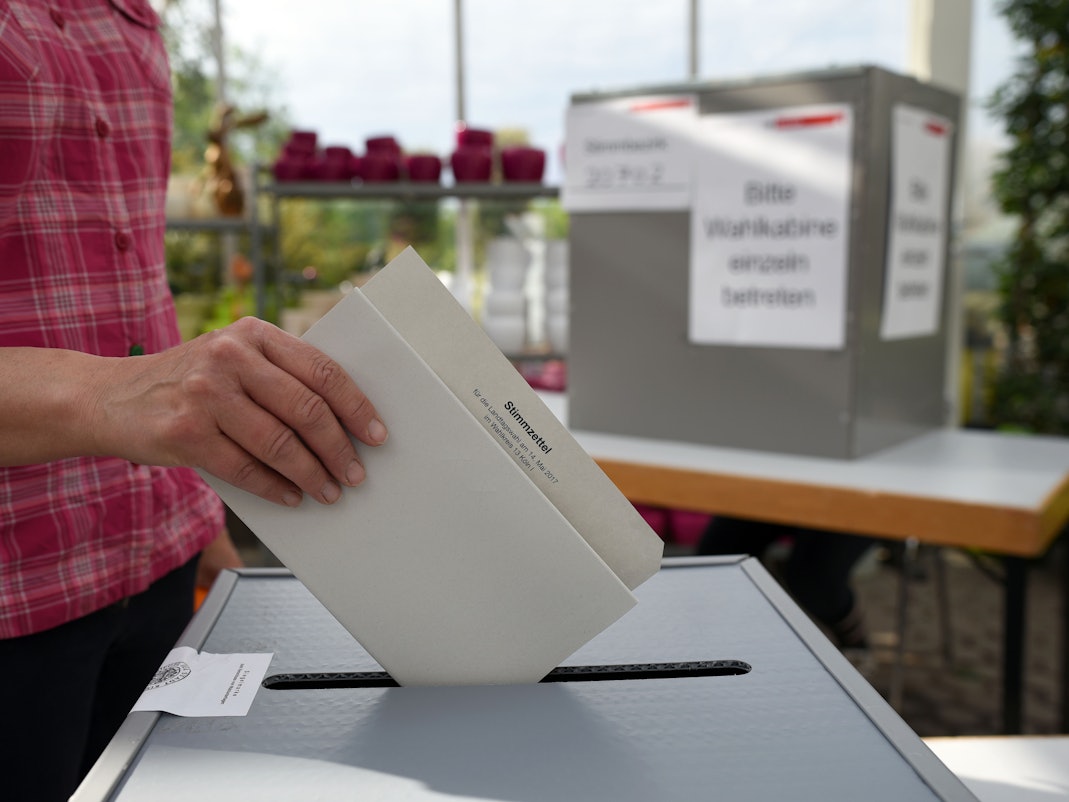 Eine Wählerin wirft in einem Wahllokal in einer Gärtnerei in Köln ihren Stimmzettel zur Landtagswahl in NRW in die Wahlurne.