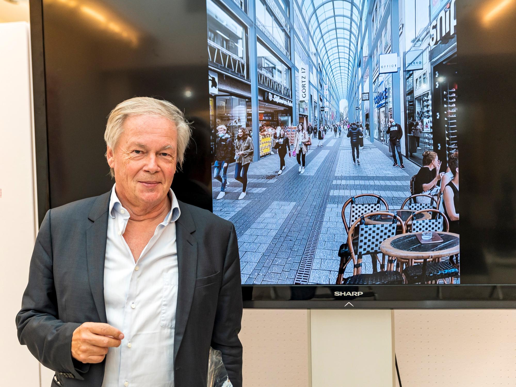 Architekt Prof. Stephan Braunfels vor einem Fernseher mit der Illustration der Hohe Straße mit einem Glasdach.