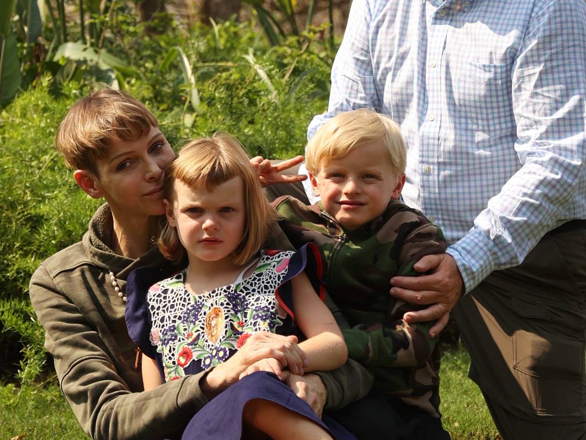 Fürstin Charlene von Monaco, ihr Mann Fürst Albert II. und ihre Kinder, die beiden Zwillinge Gabriella und Jacques sitzen in einem Garten.