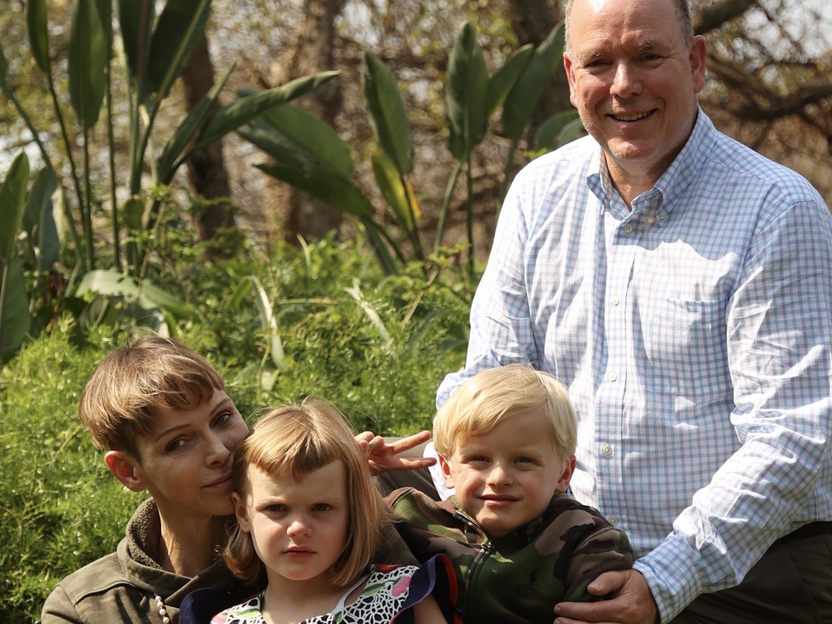 Fürstin Charlene von Monaco, ihr Mann Fürst Albert II. und ihre Kinder, die beiden Zwillinge Gabriella und Jacques sitzen in einem Garten.