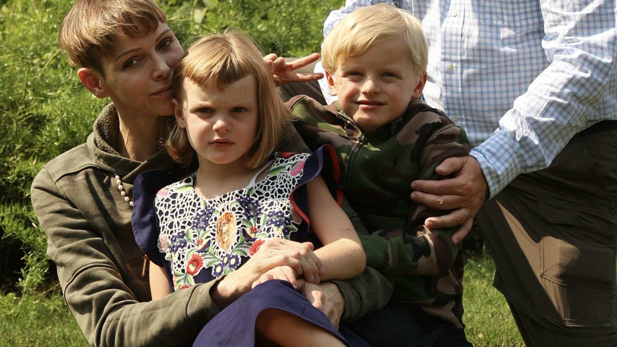 Fürstin Charlene von Monaco, ihr Mann Fürst Albert II. und ihre Kinder, die beiden Zwillinge Gabriella und Jacques sitzen in einem Garten.