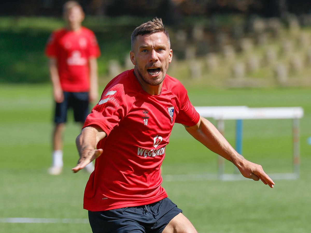 Podolski reißt auf dem Trainingsplatz den Mund auf und breitet die Arme auf.