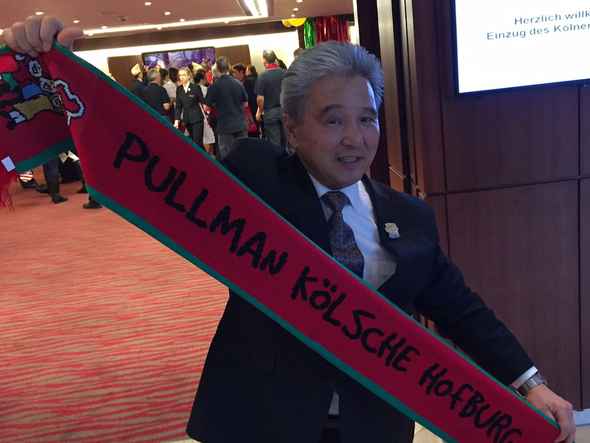 Charly Fukuhara, Barkeeper in der Hofburg, hält einen Schal hoch.