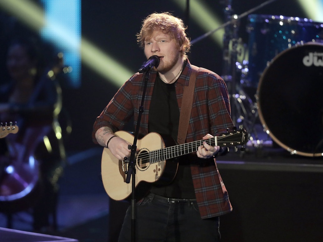 Ed Sheeran singt und spielt Gitarre auf der Bühne.