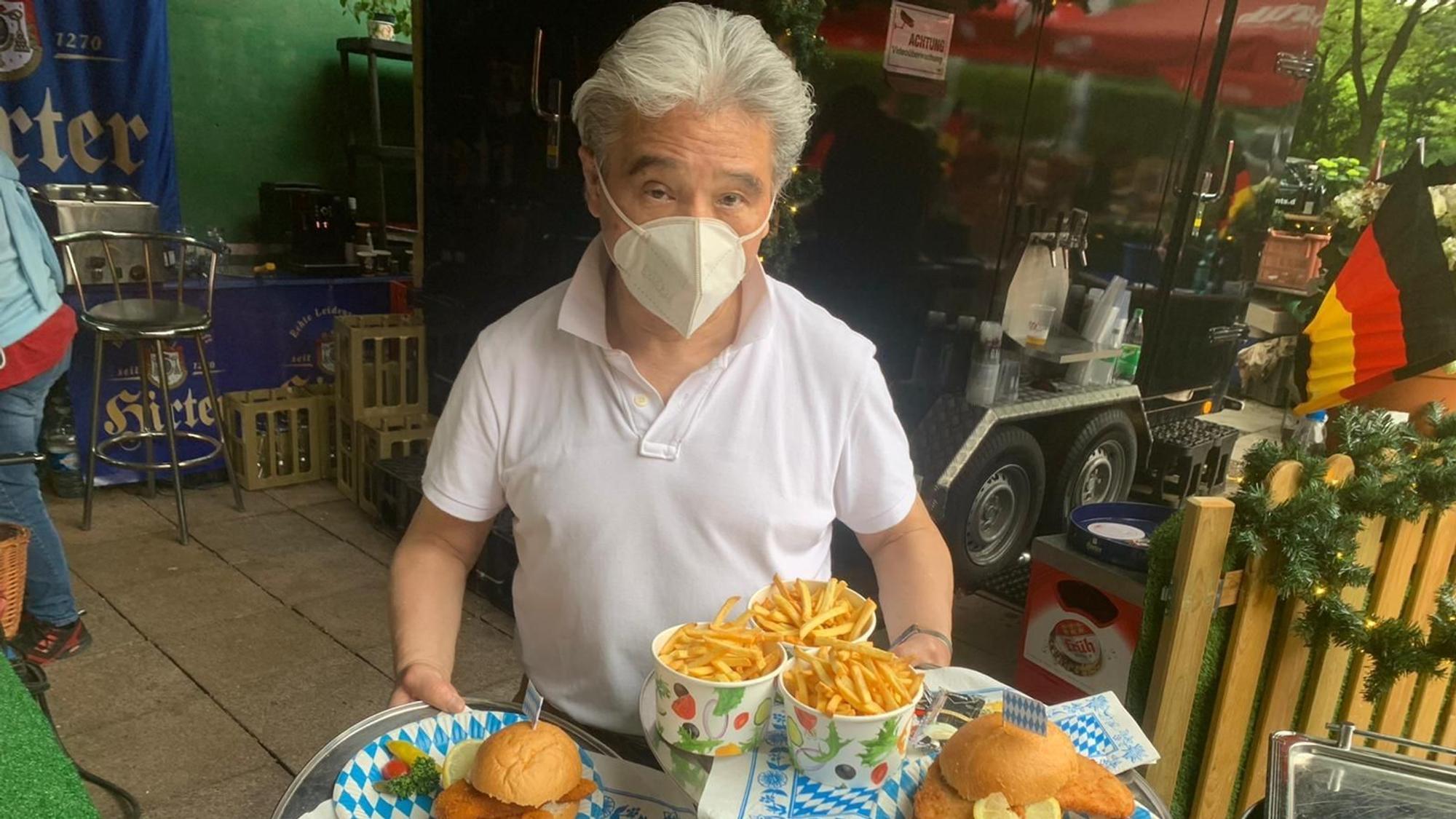 Kellner serviert Burger und Pommes.