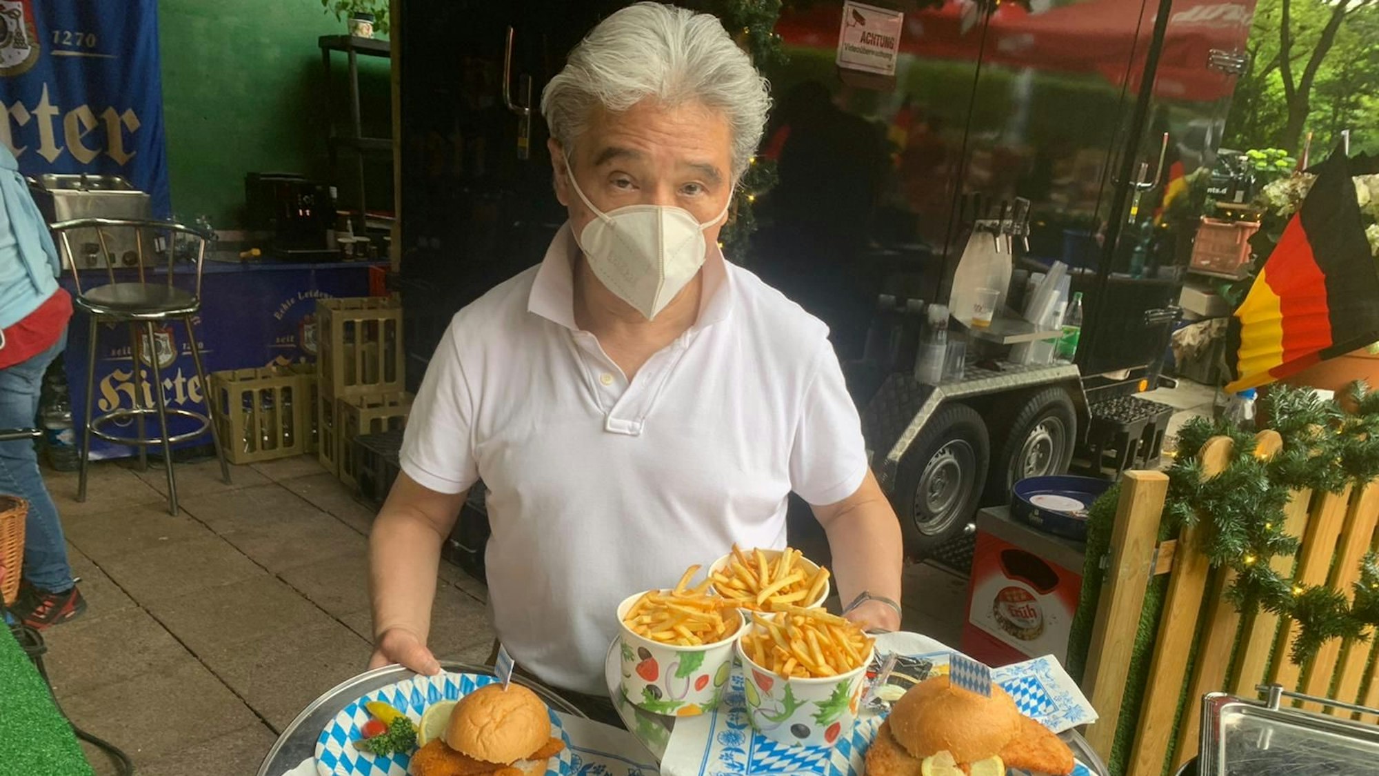 Kellner serviert Burger und Pommes.