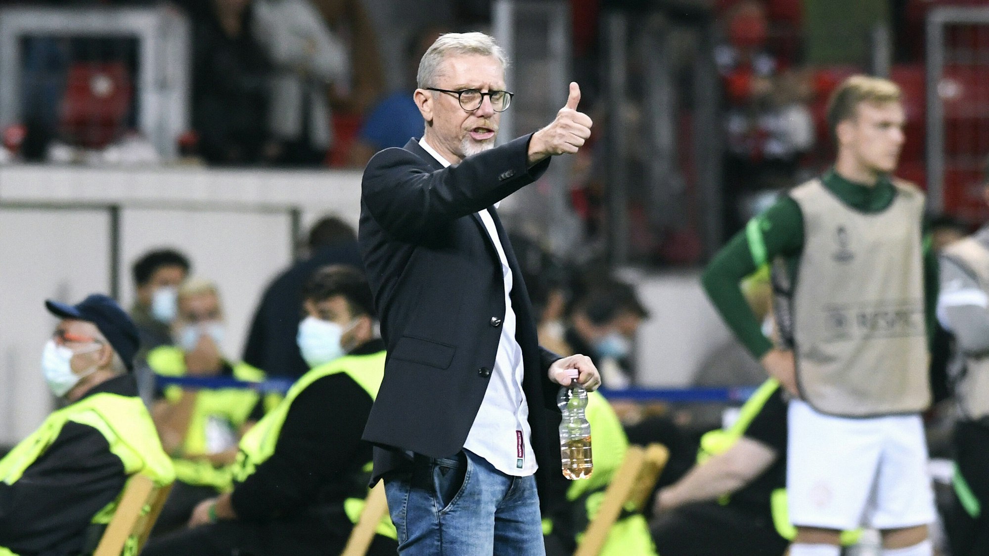 Peter Stöger zeigt mit seinem Daumen nach oben.