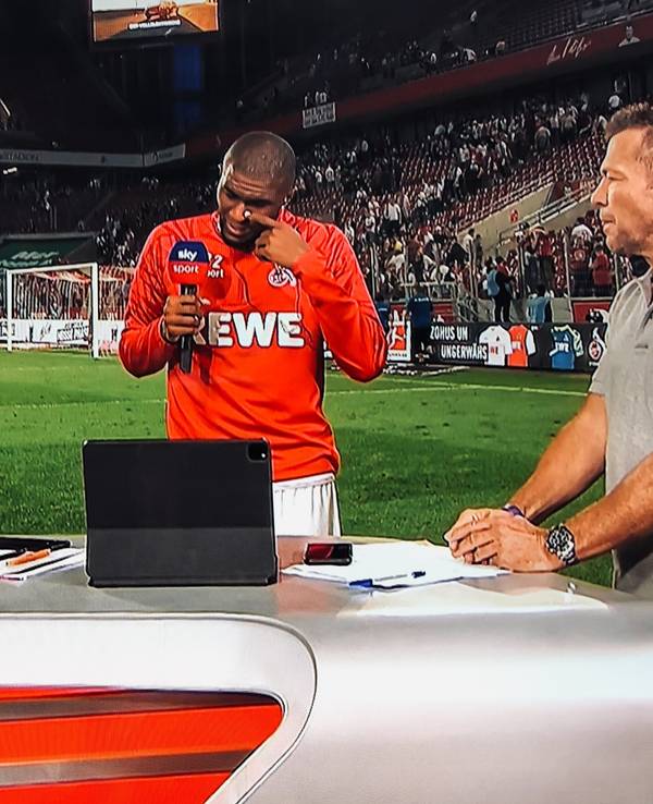 Anthony Modeste weint beim Sky-Interview mit Sebastian Hellmann (l.) und Lothar Matthäus (r.) am 18. September 2021 nach dem 1:1 des 1. FC Köln gegen RB Leipzig.