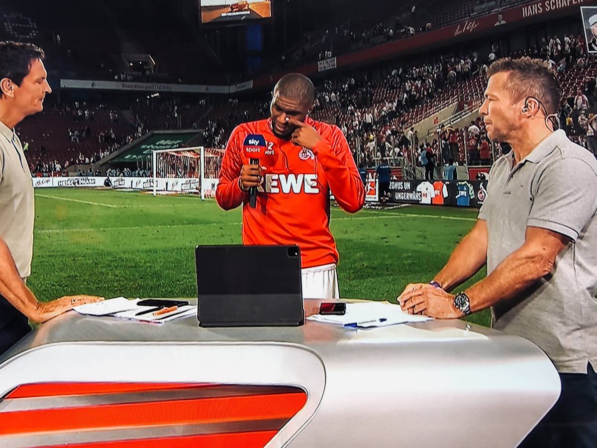 Anthony Modeste weint beim Sky-Interview mit Sebastian Hellmann (l.) und Lothar Matthäus (r.) am 18. September 2021 nach dem 1:1 des 1. FC Köln gegen RB Leipzig.