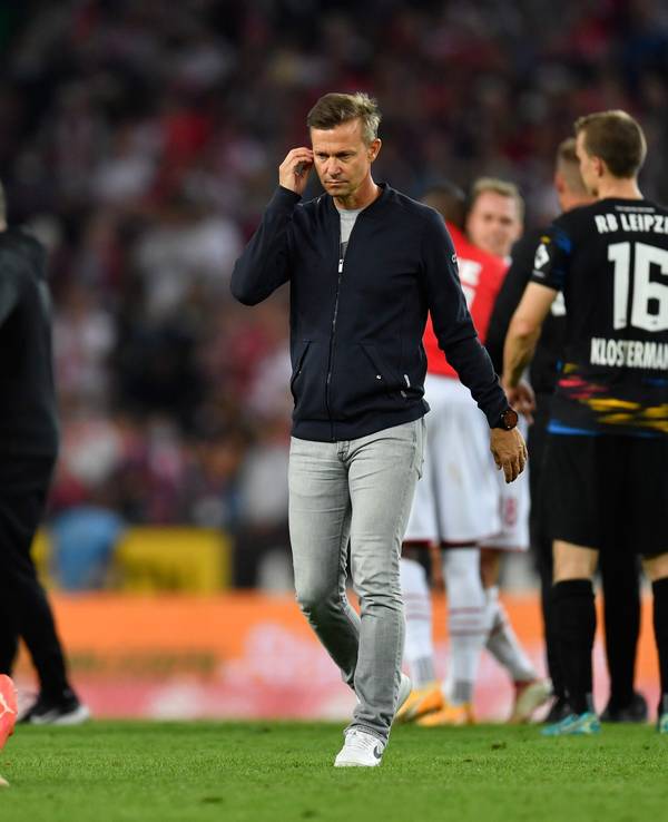 Leipzigs Trainer Jesse Marsch (r) geht nach dem Spiel über den Platz. Links sitzt Leipzigs Mohamed Simakan auf dem Rasen.