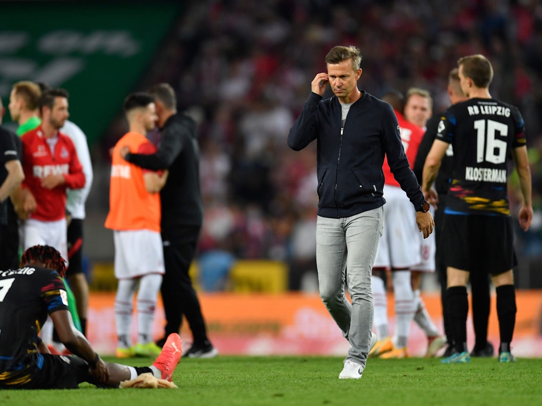 Leipzigs Trainer Jesse Marsch (r) geht nach dem Spiel über den Platz. Links sitzt Leipzigs Mohamed Simakan auf dem Rasen.