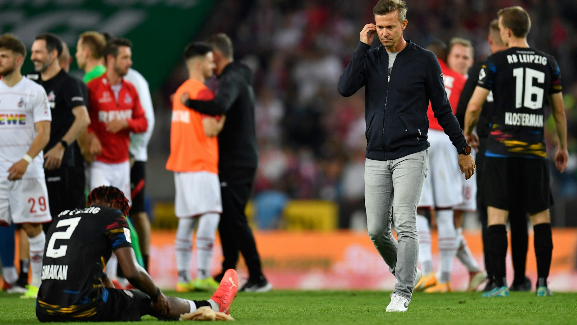 Leipzigs Trainer Jesse Marsch (r) geht nach dem Spiel über den Platz. Links sitzt Leipzigs Mohamed Simakan auf dem Rasen.