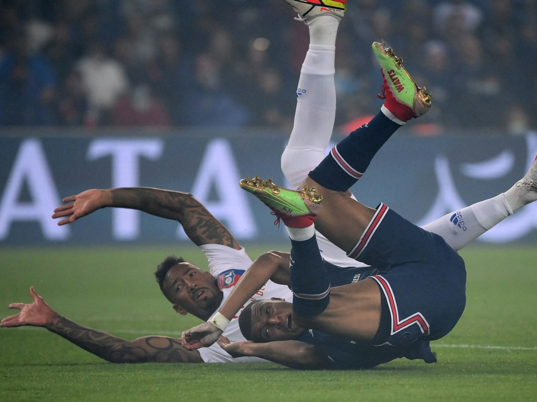 Paris Saint-Germains Kylian Mbappe fällt mit Lyons Jerome Boateng auf den Rasen.