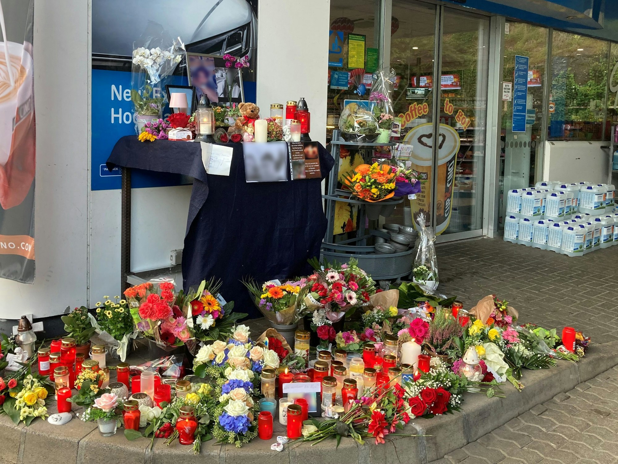 Blumen und Kerzen sind vor der Tankstelle aufgestellt, in der ein 20-jähriger Kassierer mit einem Kopfschuss getötet wurde.