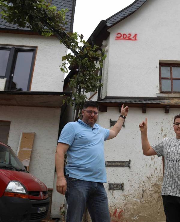 Familie in Dernau zeigt Pegelstand des Hochwassers von Juli 2021