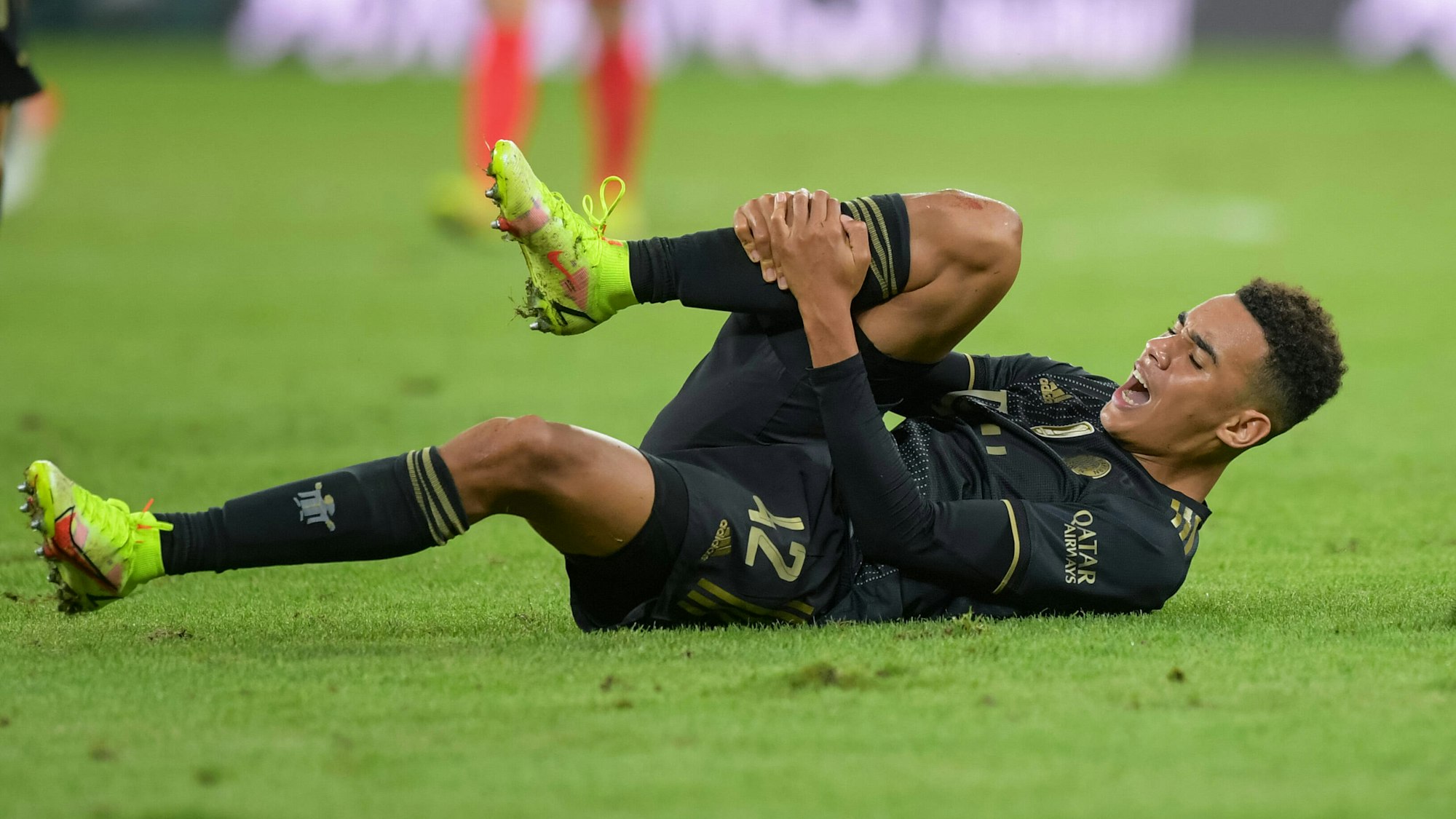 Bayerns Jamal Musiala hält sich schmerzverzerrt das rechte Schienbein.