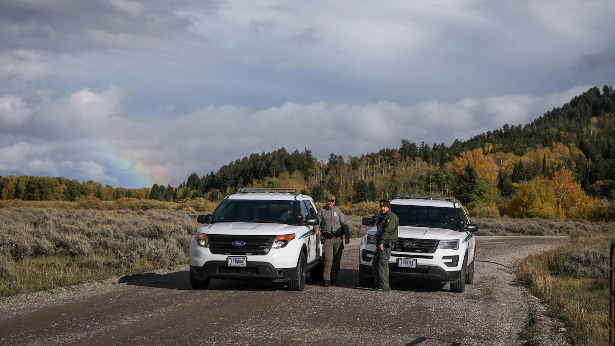 Beamte der U.S. Park Ranger blockieren den Zugang für Fahrzeuge mit zwei SUVs. Sie stehen auf einer Schotterstraße, hinter ihnen ist ein Waldstück zu sehen.