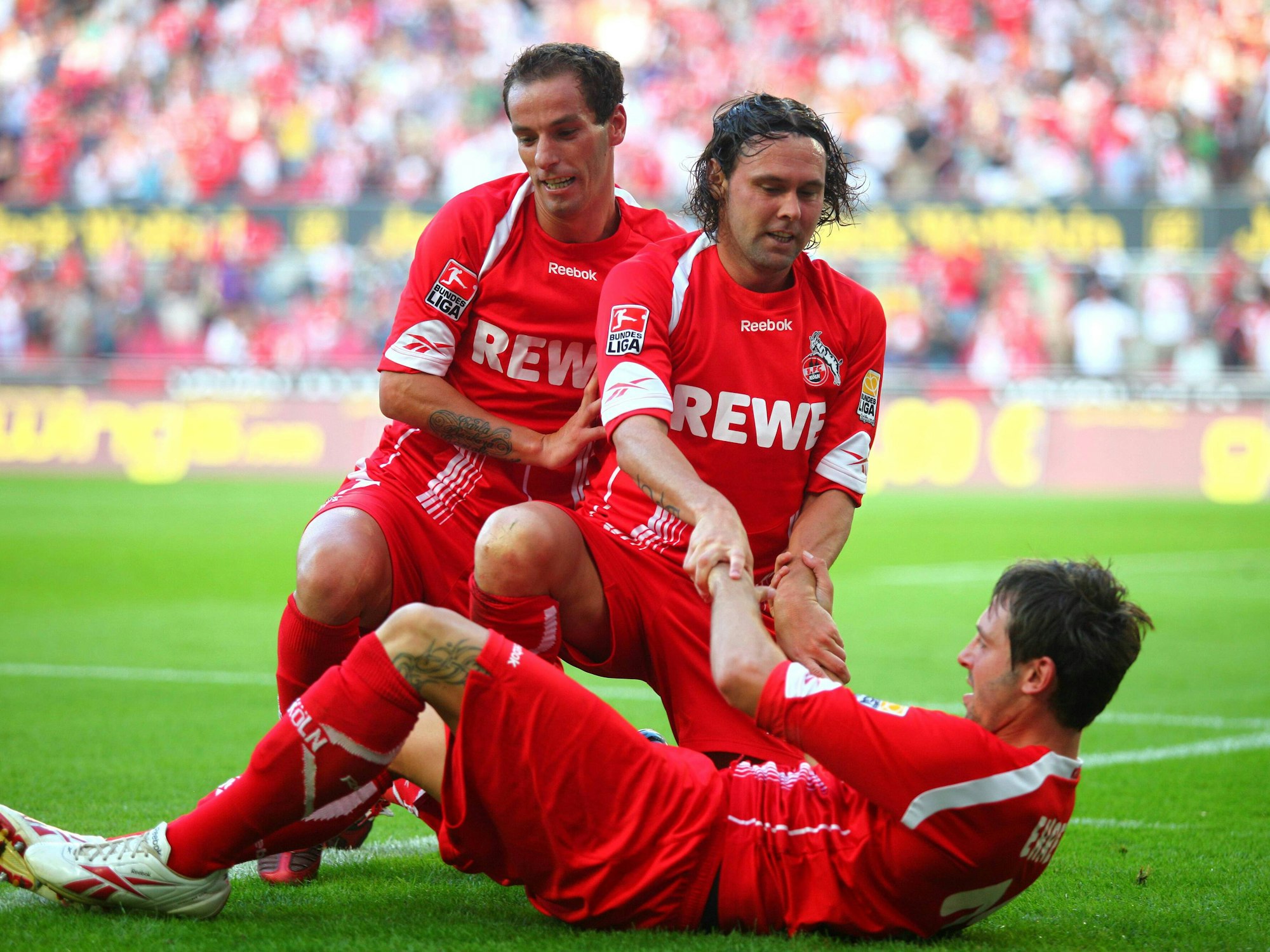 Fabrice Ehret liegt am Boden. Petit und Maniche hocken vor ihm. Maniche greift nach Ehrets Armen.