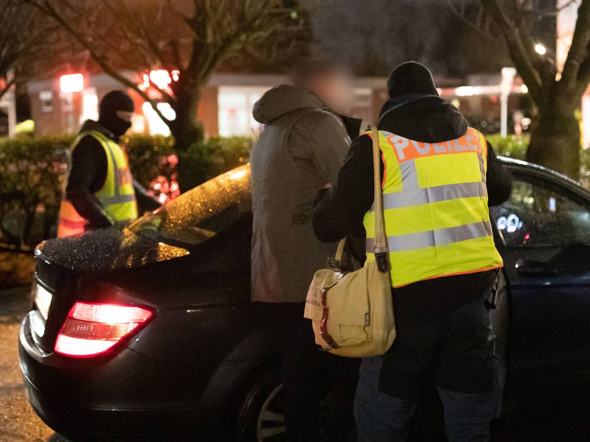 Polizist führt Verdächtigen ins Auto.