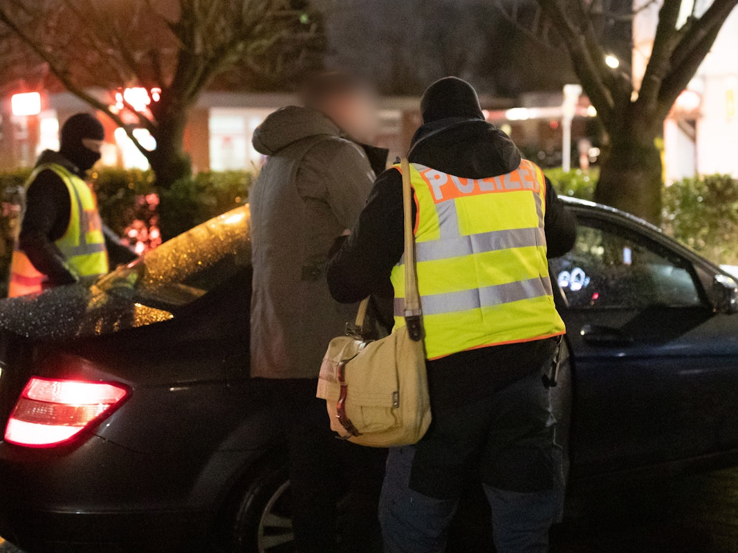 Polizist führt Verdächtigen ins Auto.