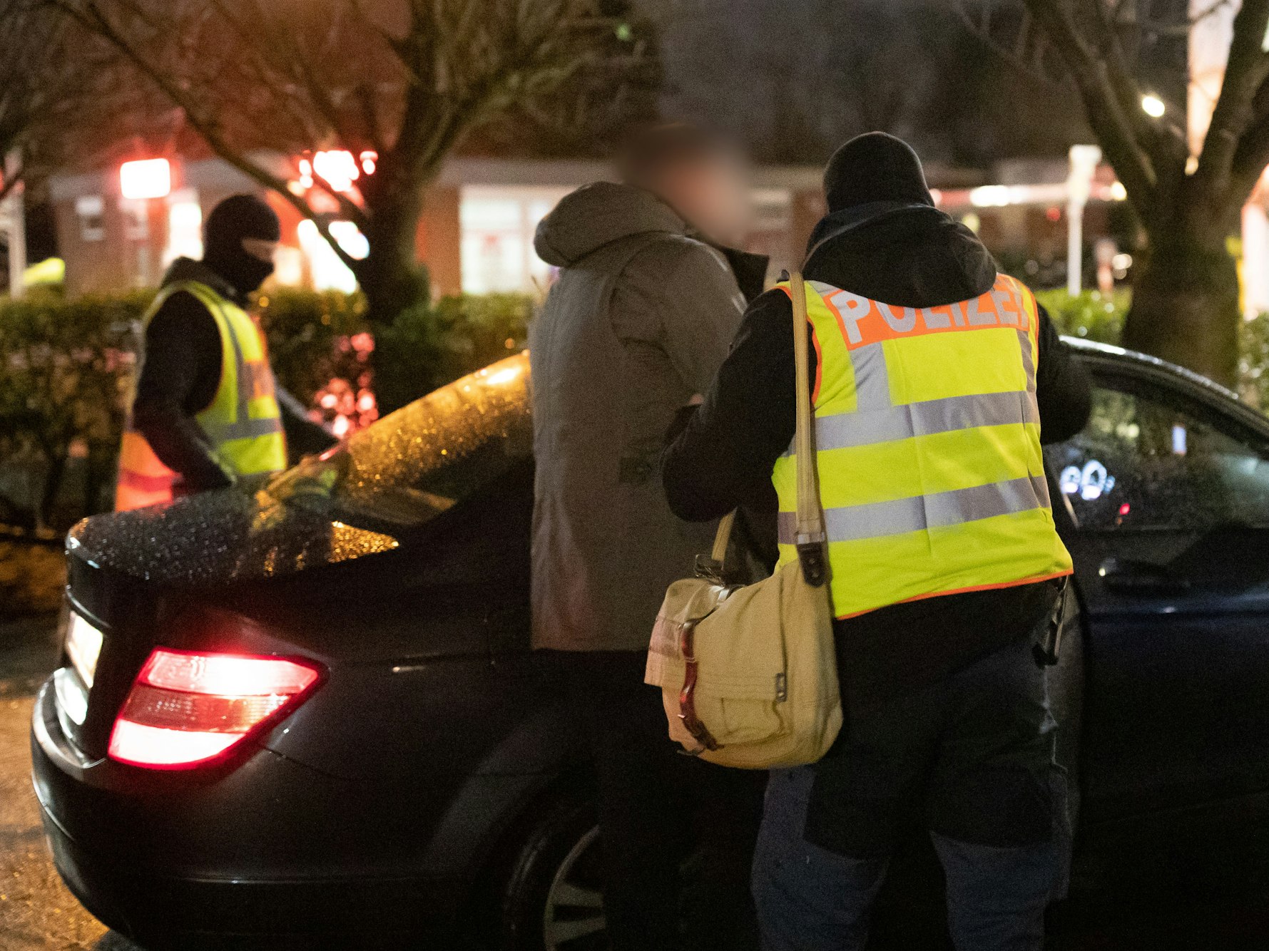 Polizist führt Verdächtigen ins Auto.