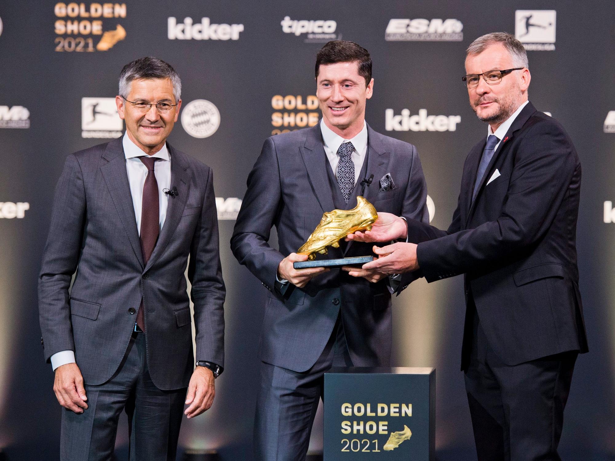Jörg Jakob überreicht Robert Lewandwoski den Goldenen Schuh. Herbert Hainer steht daneben