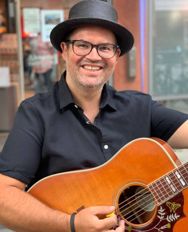 Björn Heuser hält eine Gitarre in der Hand.