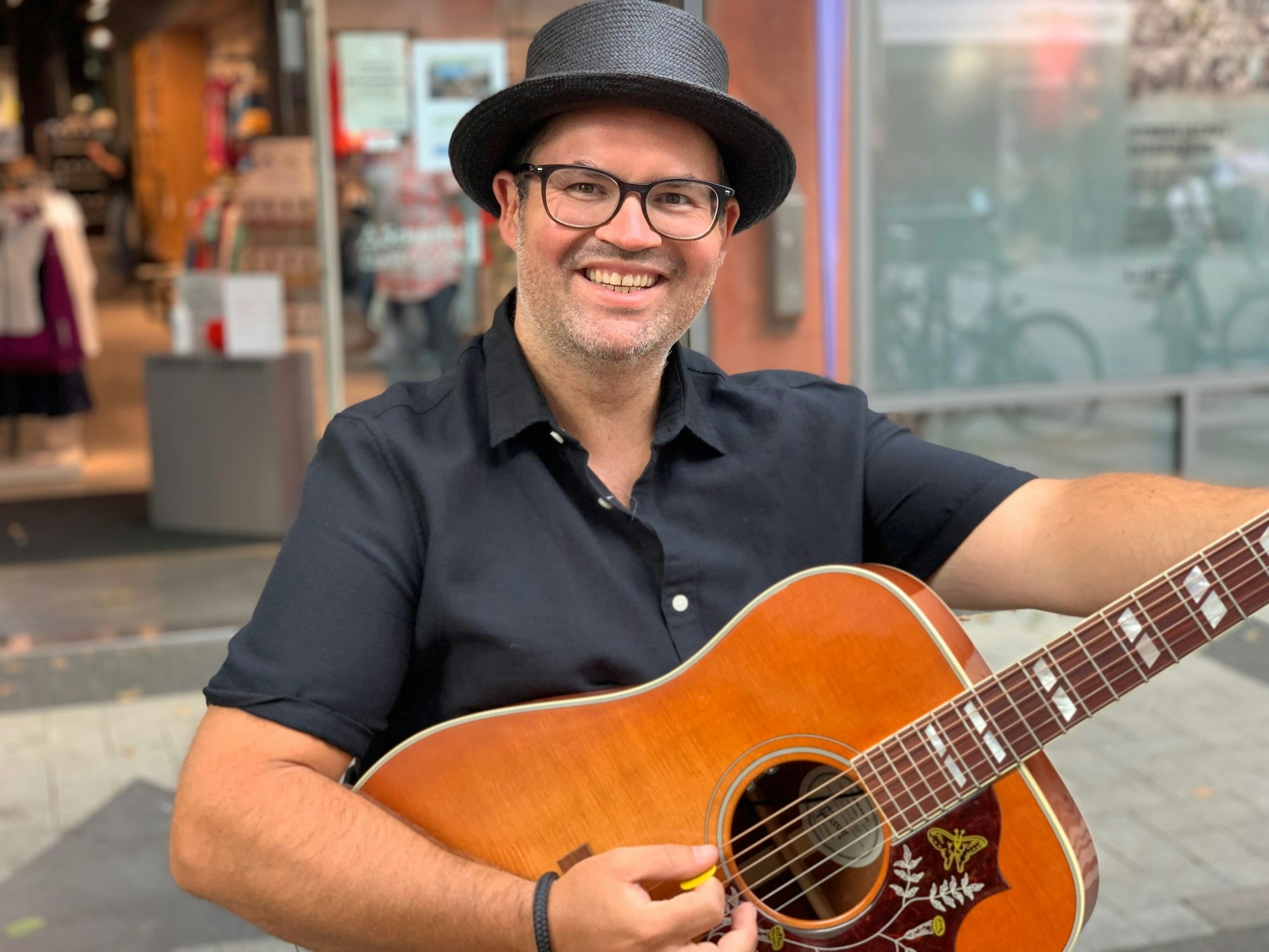 Björn Heuser hält eine Gitarre in der Hand.