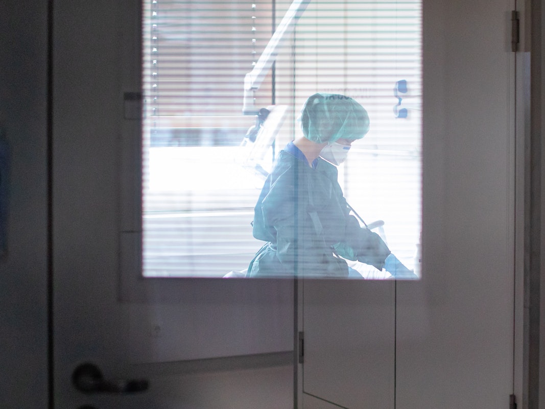 Eine Krankenschwester auf der Infektionsstation der Uniklinik Essen versorgt in Schutzkleidung und mit einer Atemmaske einen Patienten.